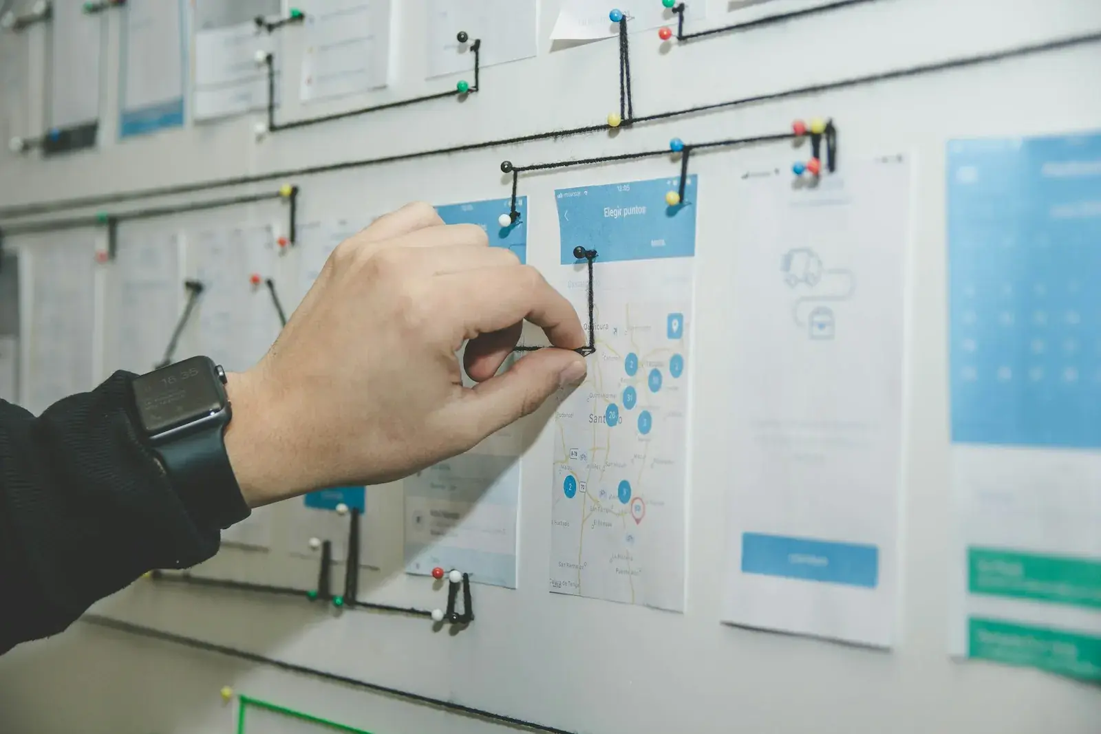 Printed application screens pinned to a wall and connected into a user flow